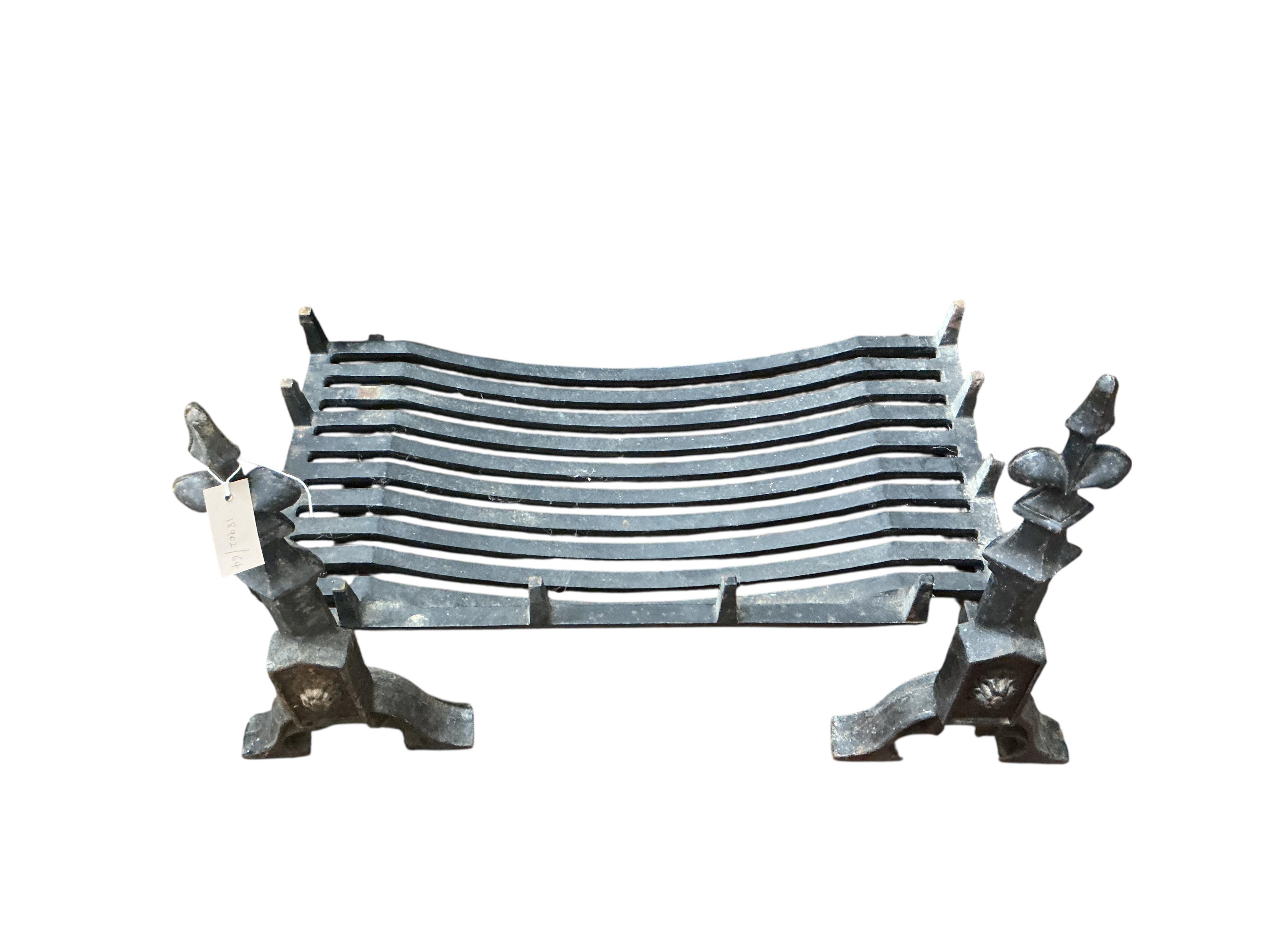 A wrought iron grate with fleur de lys dogs, width 76cm, depth 50cm, height 56cm (lacking one bolt)